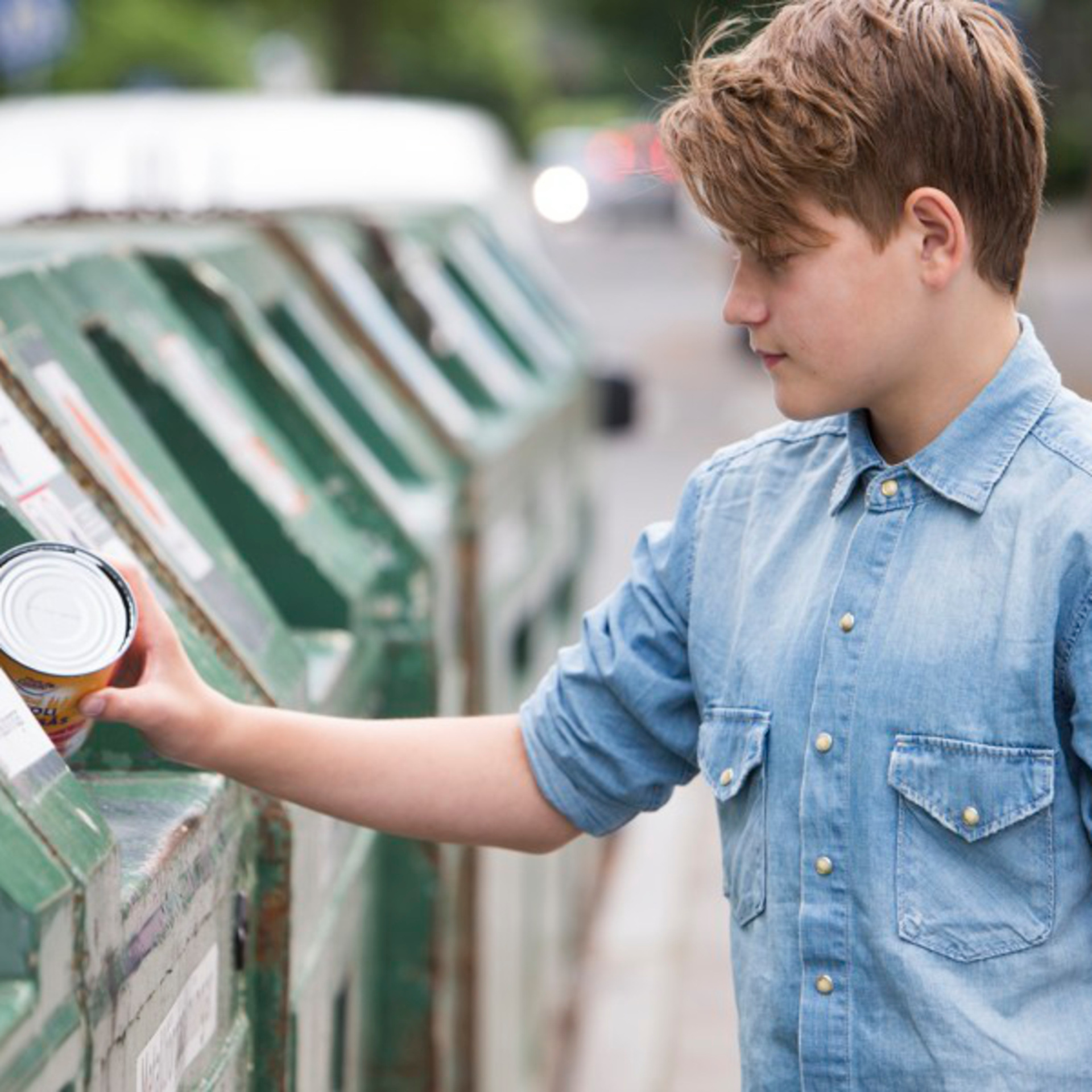 pojke stoppar in en tom förpackning till återvinning på återvinningsstation