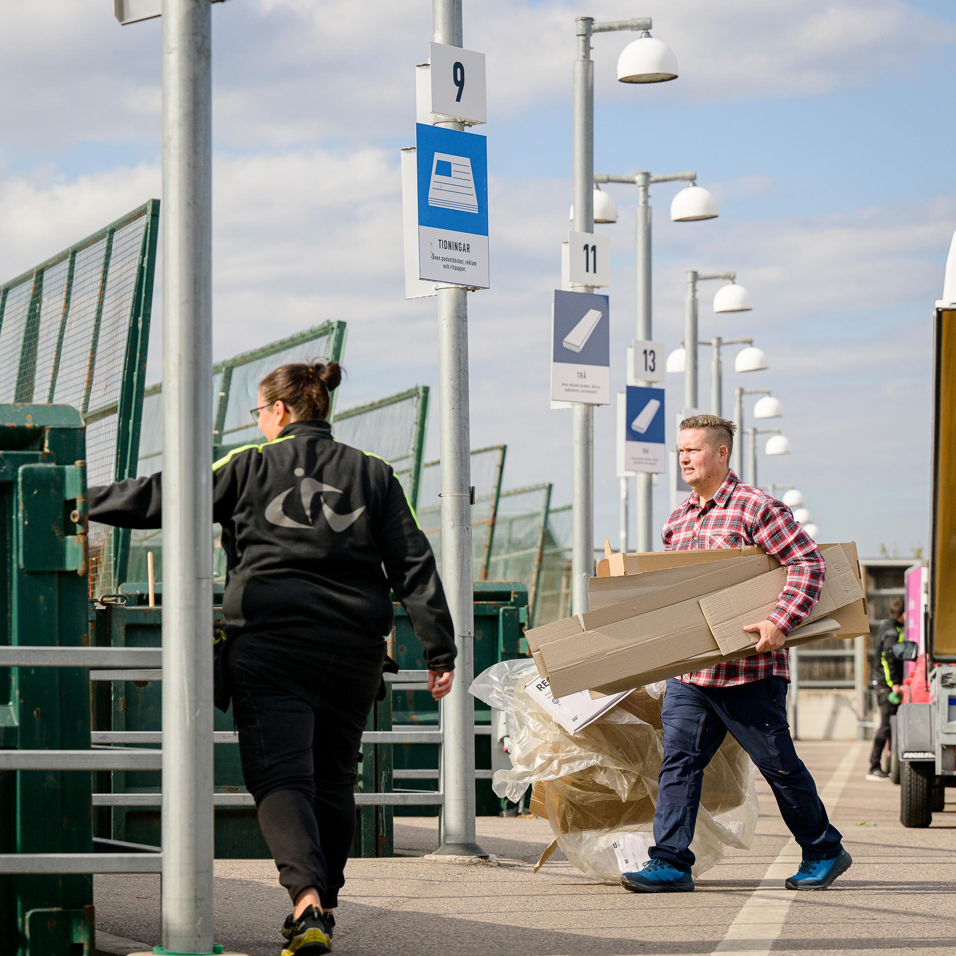 Kvinna på återvinningscentral pekar mot container